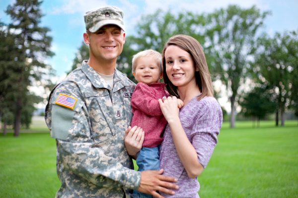 Real American soldier with wife and son smiling outdoor.